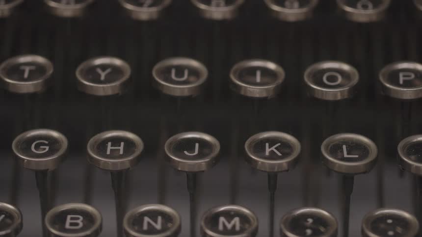 Rows of round glasstopped typewriter keys with white letters on black backgrounds