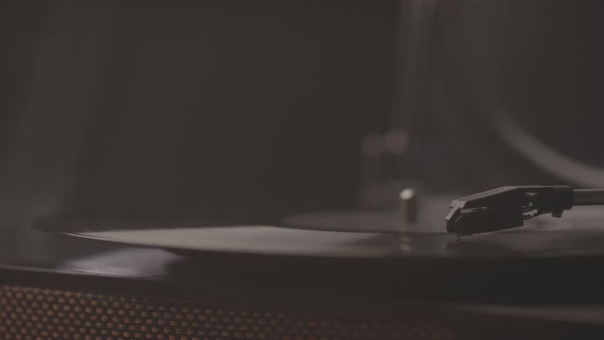 The video shows a closeup of a record player with a record spinning on it the needle arm is visible but the needle has not yet dropped onto the record