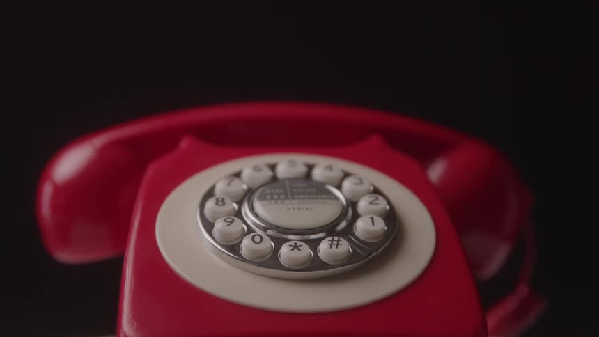 A red rotary phone is rotating