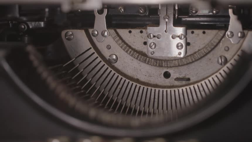 The video shows a closeup of the inner workings of a vintage typewriter the metal typebars rise and fall in a circular motion showcasing the intricate mechanics of the machine