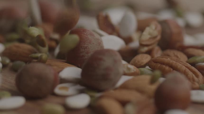 Seeds and nuts falling onto a wooden surface