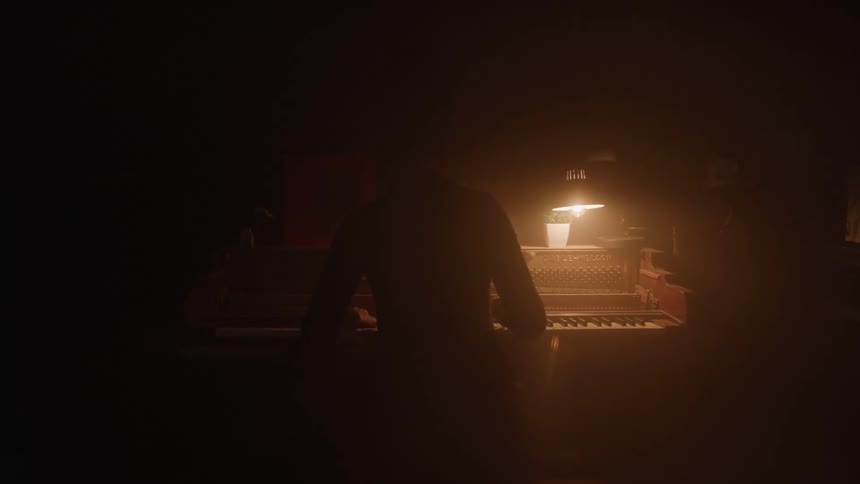A man is playing the piano in the dark