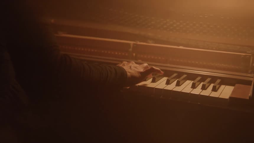 Woman wearing a long sleeved black dress plays the piano
