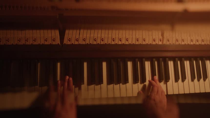 Female pianist plays the piano keyboard causing the inner hammers to move
