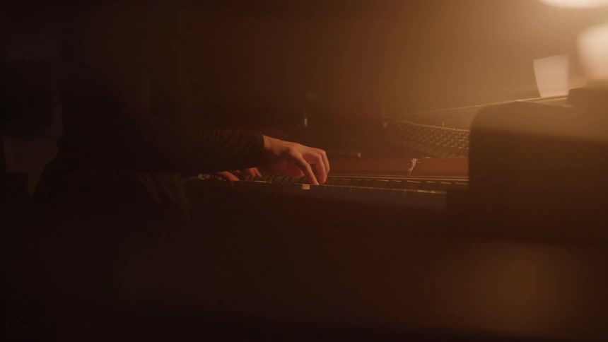 Female pianist sitting in a dimly lit area plays the piano