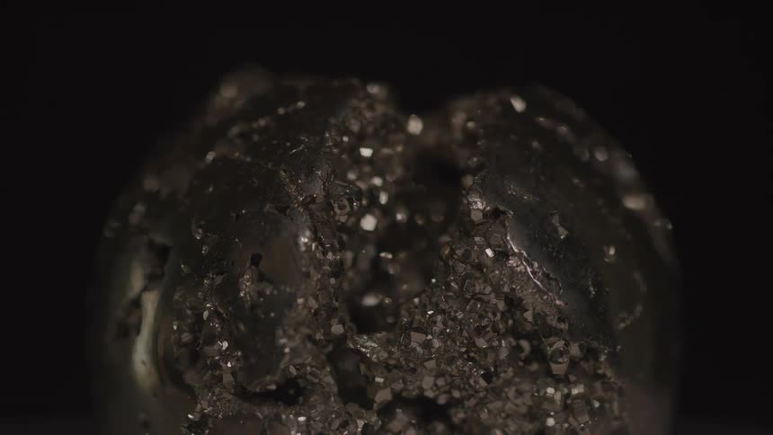 A close view shows a small carved piece of dark mineral with sparkling pieces embedded in its surface and interior