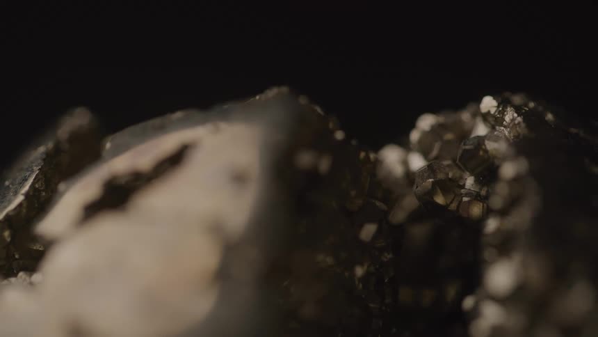 The video shows a closeup of a sparkling dark mineral possibly a crystal rotating slowly the light reflects off its many facets