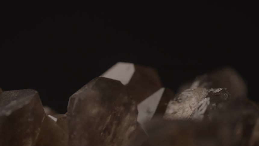Smoky quartz crystal points highlighted against a dark background
