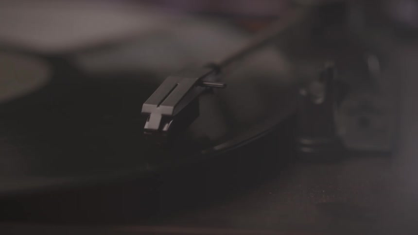 A record players tonearm rests on a spinning vinyl record