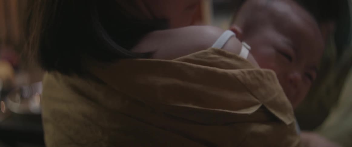 A woman holding a crying baby stands