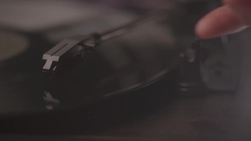 The video shows a finger gently placing the needle onto a vinyl record with the record itself spinning the scene is a closeup shot that highlights the record players needle and the grooves of the vinyl