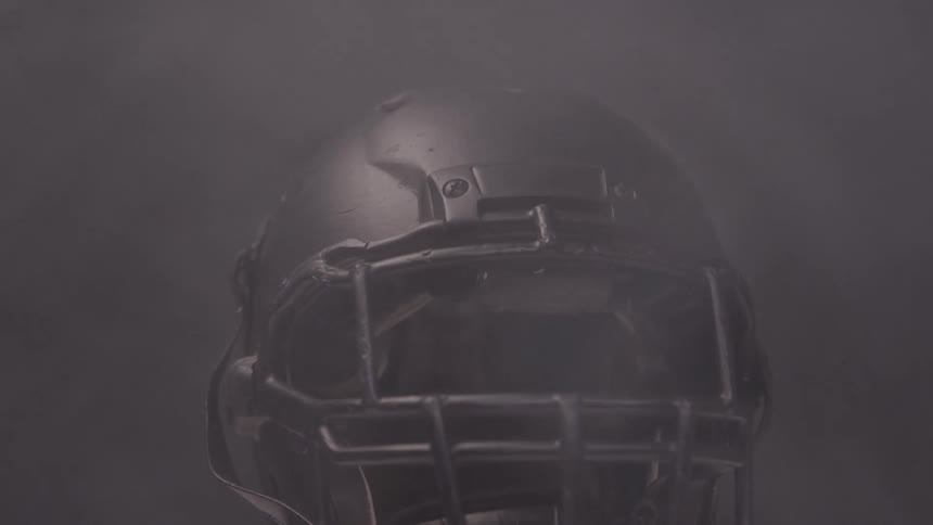 Black american football helmet with front bars surrounded by mist