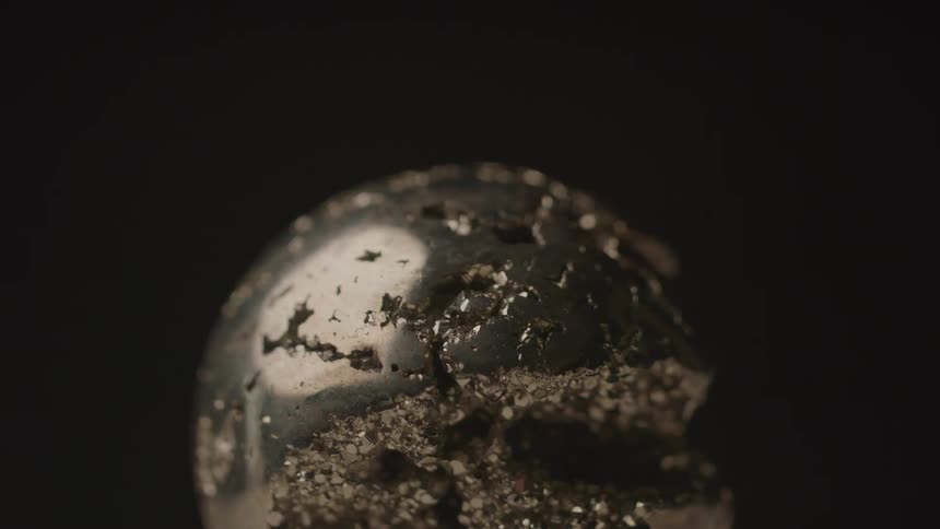 Metallic skull partially covered with sand grains