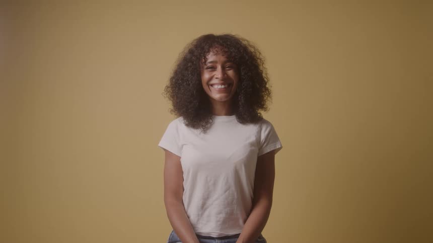 Smiling curly haired woman in a room with a yellow background