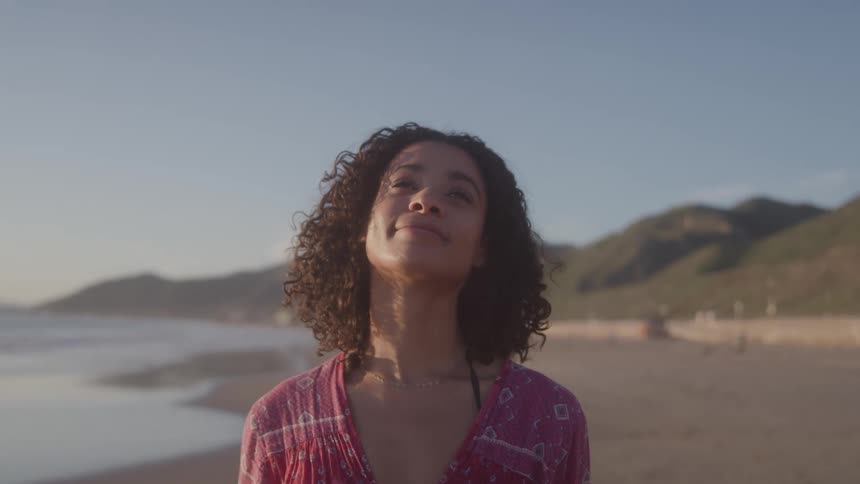 Close up portrait of a young black woman outdoors at the beach during daytime