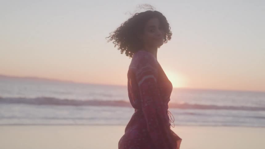 Woman in a pink dress on the beach at sunset