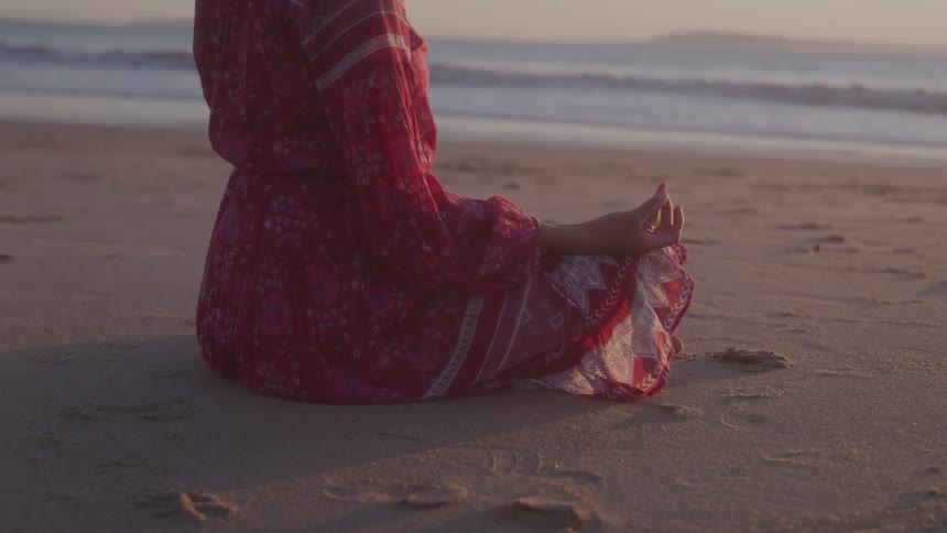 A woman meditates on the beach