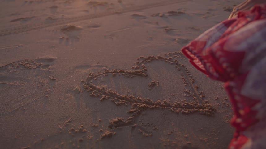 A girl traced a heart in the sand