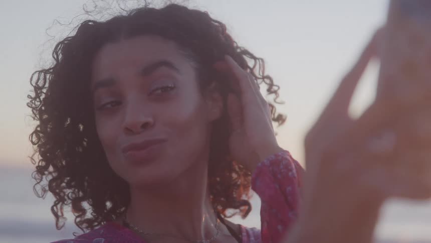 A woman using her phone to record a selfie smiling and happy