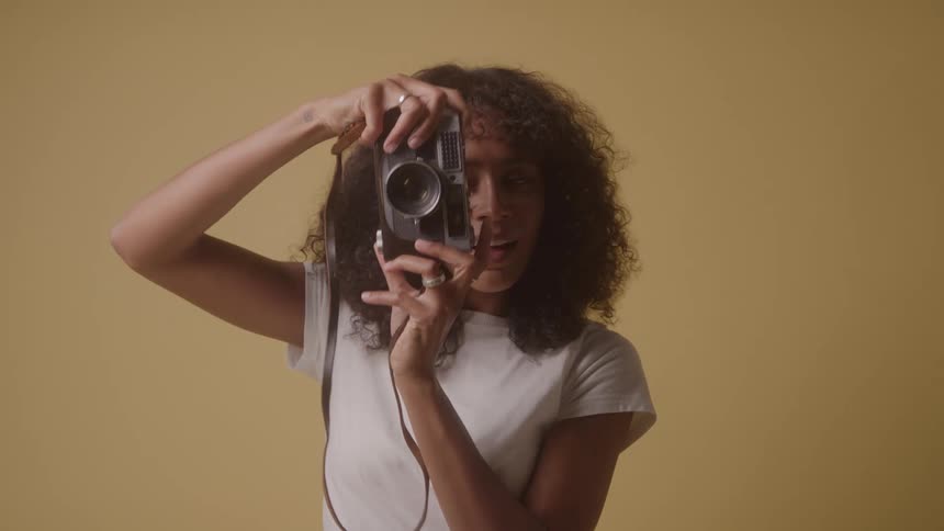 Smiling curly haired woman taking a photo with a vintage camera