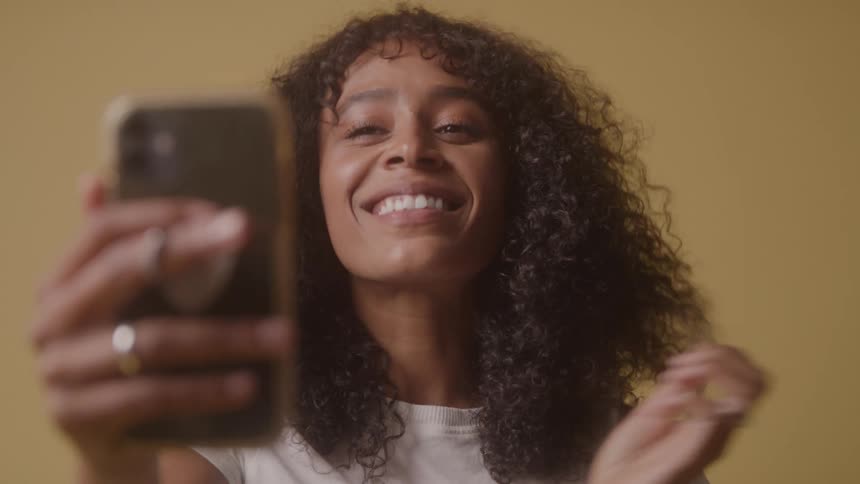 Woman holding a cellphone while touching her hair with the other hand