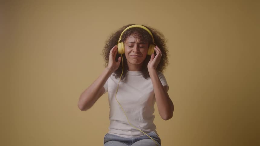 A woman is dancing and listening to music on headphones
