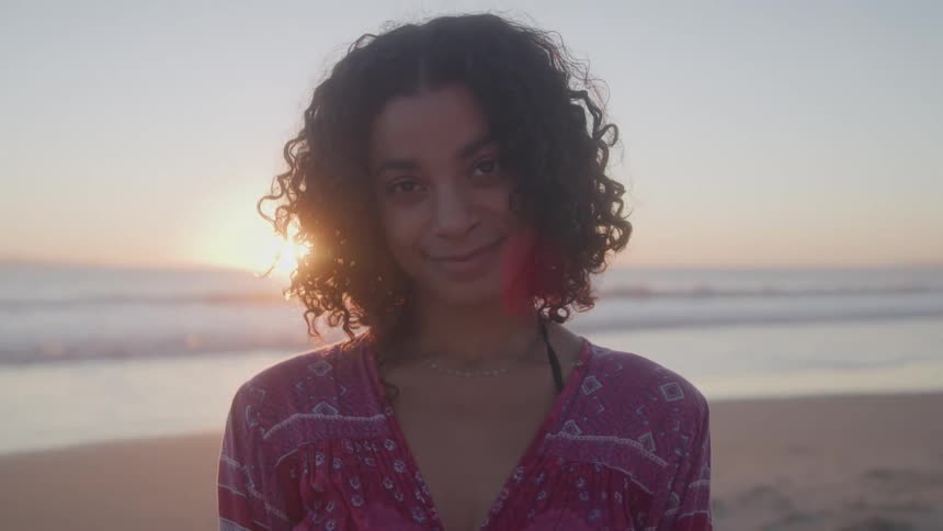 A happy smiling woman on the beach with a beautiful sunset at the end of the shore