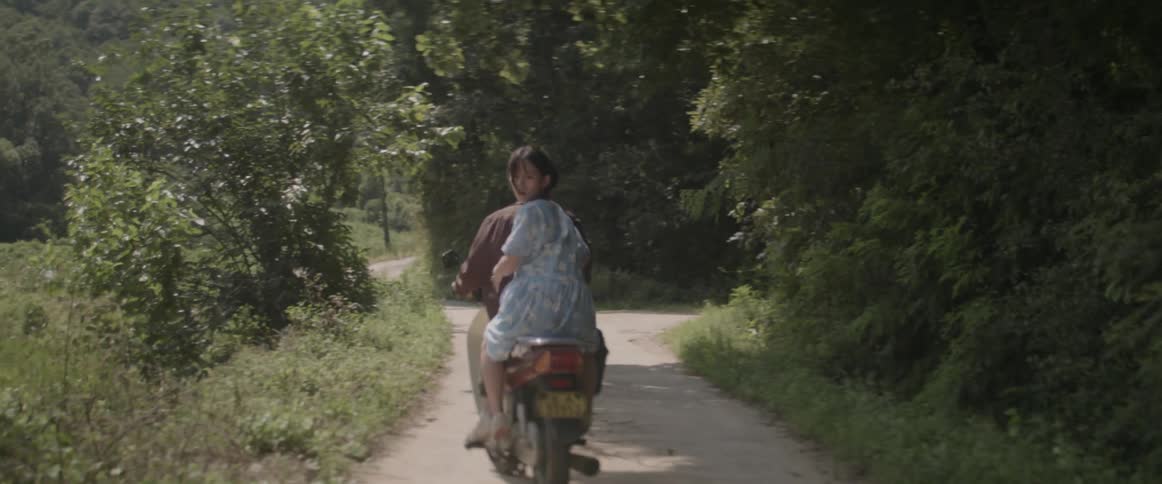 A man and a woman riding off on a motorcycle