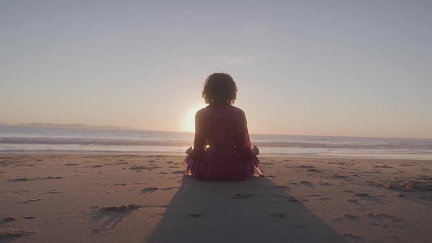 Person sitting on the beach watching the sunset