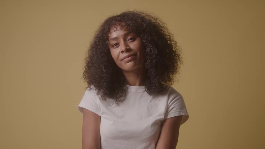 Curly haired woman in white shirt against a yellow background