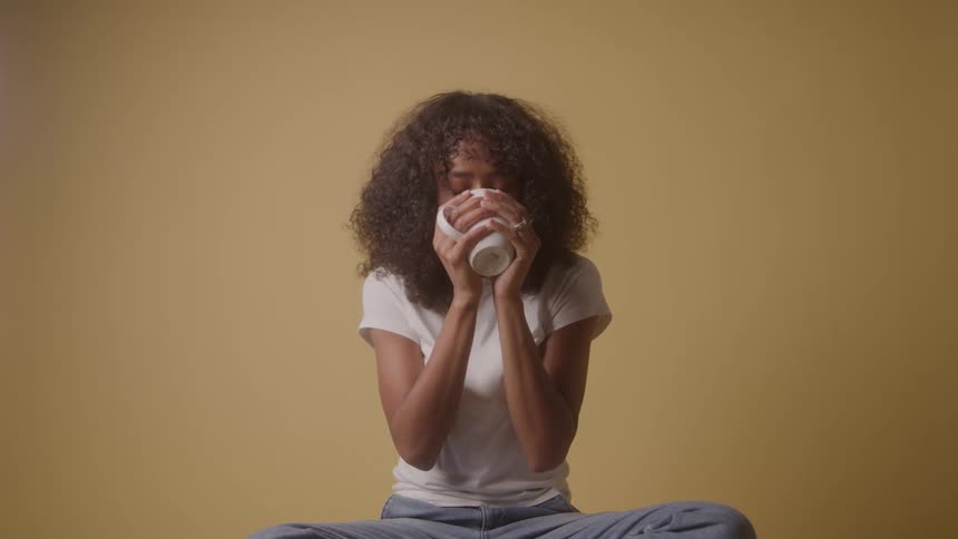 A woman drinks coffee and smiles