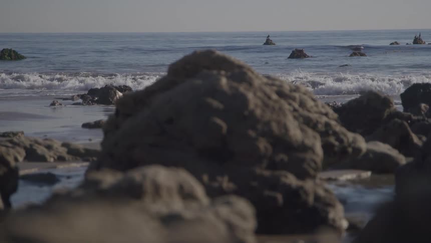 Rocks on wet sand with the sea in the background