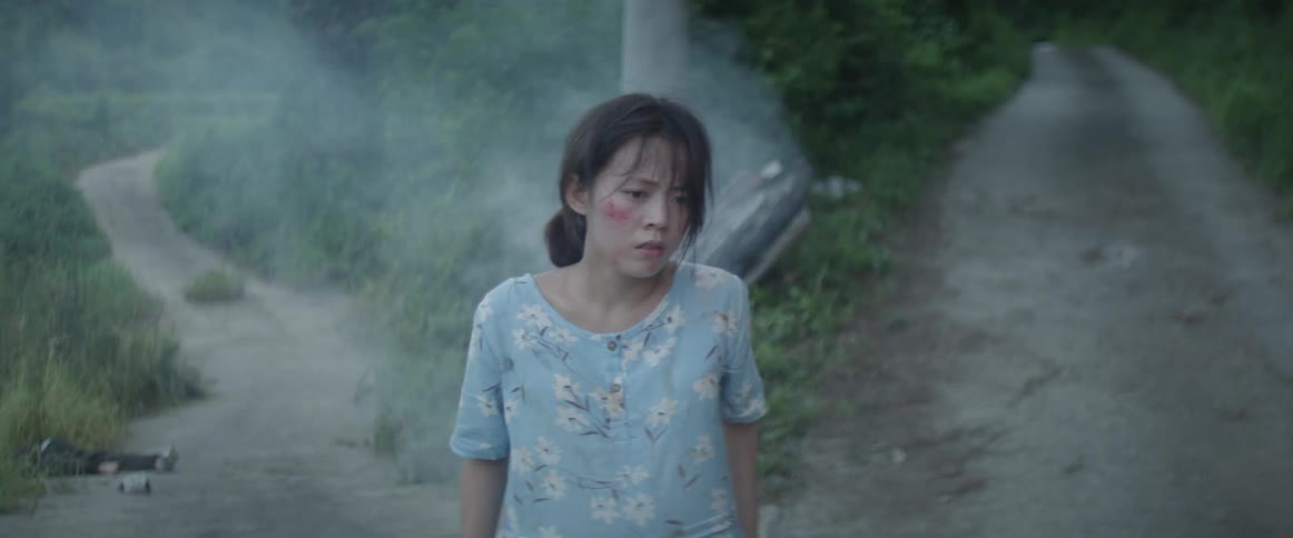 An asian woman stands up in front of a crashed motorcycle