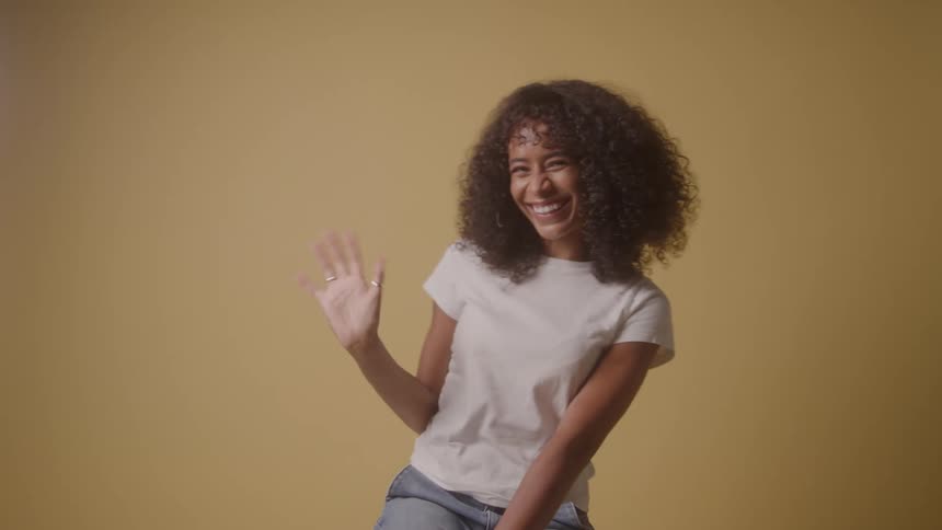 The woman is smiling and waving