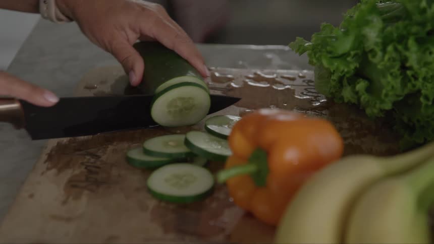 A person slices up a cucumber