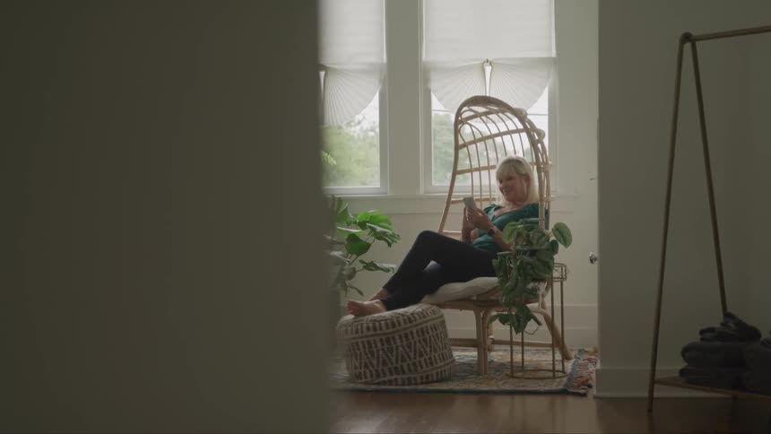 A woman sits in her bedroom using her cell phone