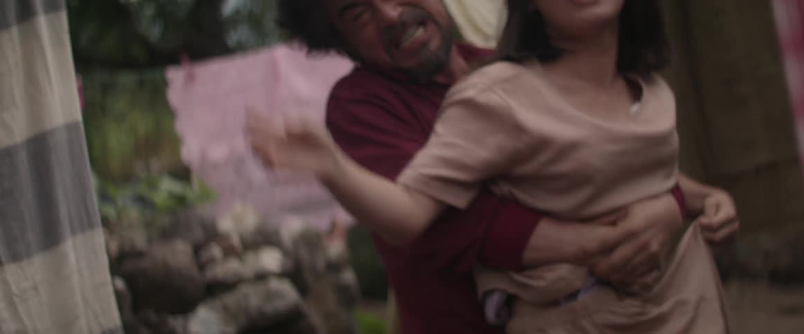 A man restrains a screaming woman near clothes lines