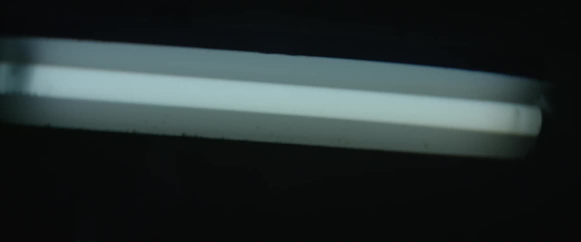 A fluorescent light sways in a dark room