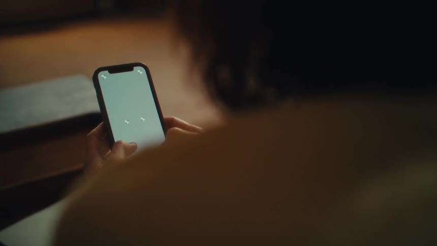 Back of a woman texting on cell phone indoors