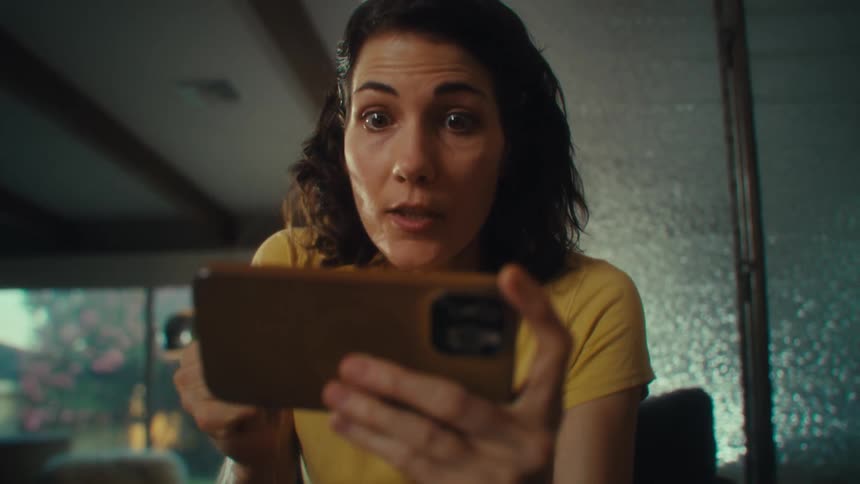 Woman smiling and raising her arm in celebration while holding a smartphone