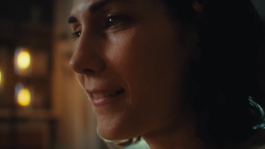Woman smiling while holding a cellphone with blurred lights in the background