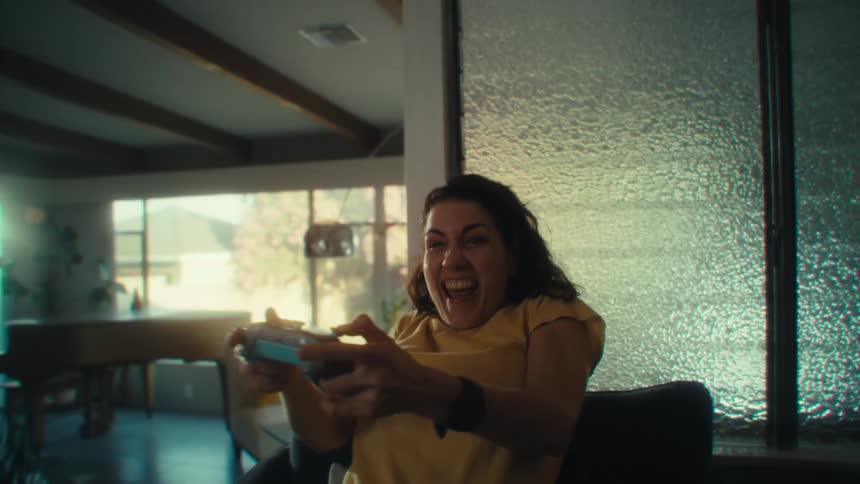 Woman sitting in an armchair playing video games and celebrating happily