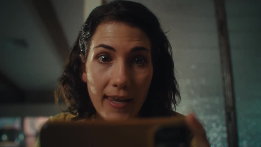 Woman celebrating while holding and watching on a smartphone