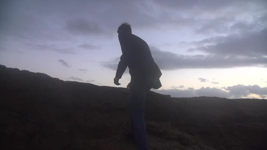 Man walking up a hill on a cloudy day