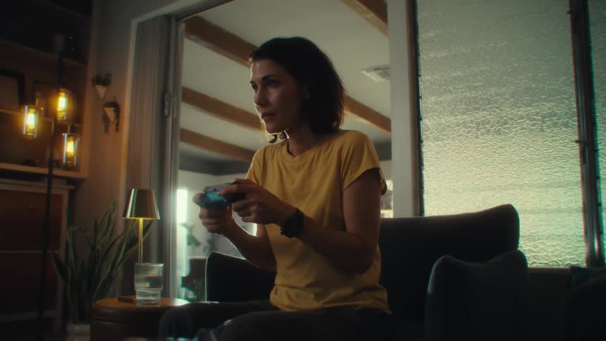 Woman sitting in an armchair having fun playing video games