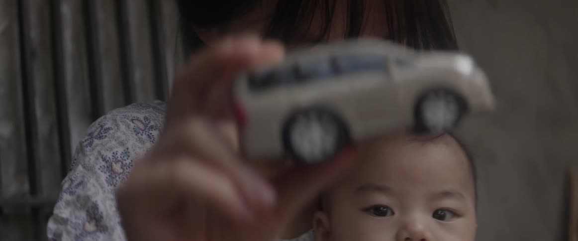 A woman plays with a toy holding her baby