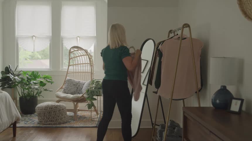 Woman choosing clothes in front of a mirror in the bedroom