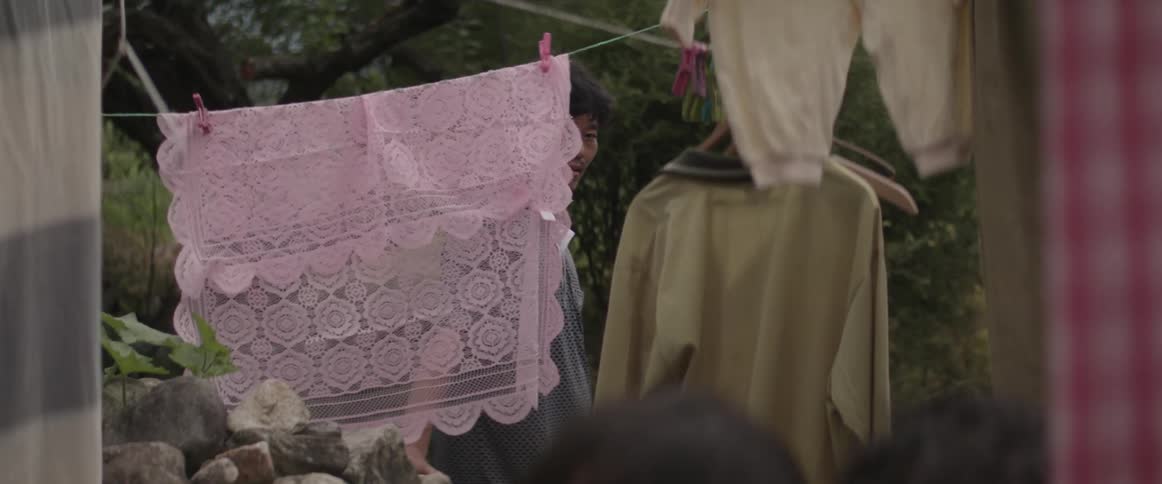 People moving and laughing amongst clotheslines outdoors