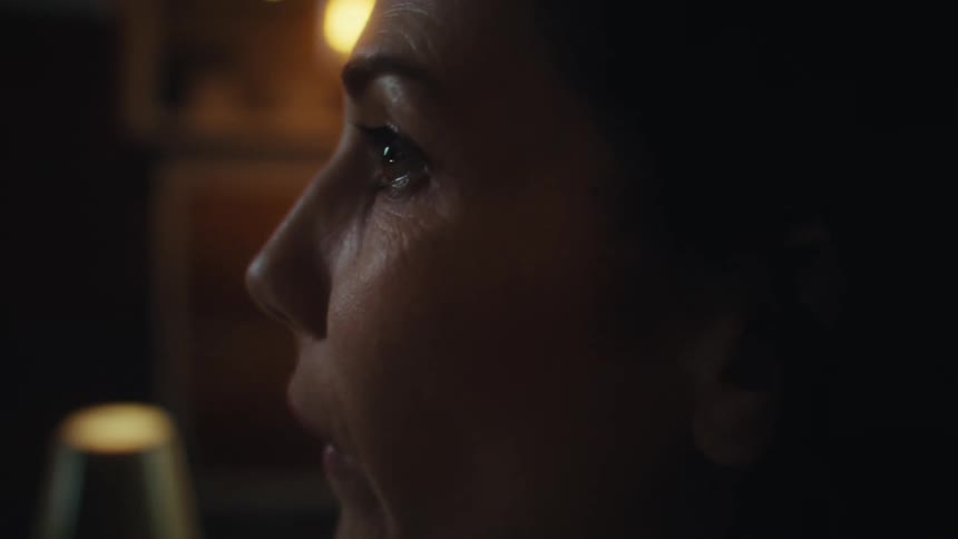 A woman engaging in an intimate conversation across the table in a dimly lit restaurant