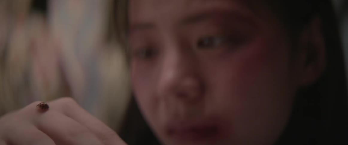 An asian woman stares at a crawling insect on her hand